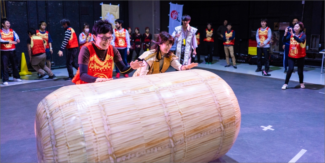 戦国運動会に参加して俵を転がす男女